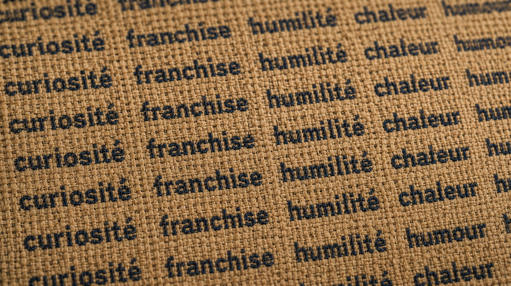 Gros plan sur une trame de lin tissée portant les mots curiosité, franchise, humilité, chaleur, humour — métaphore du caractère d'un modèle d'IA générative